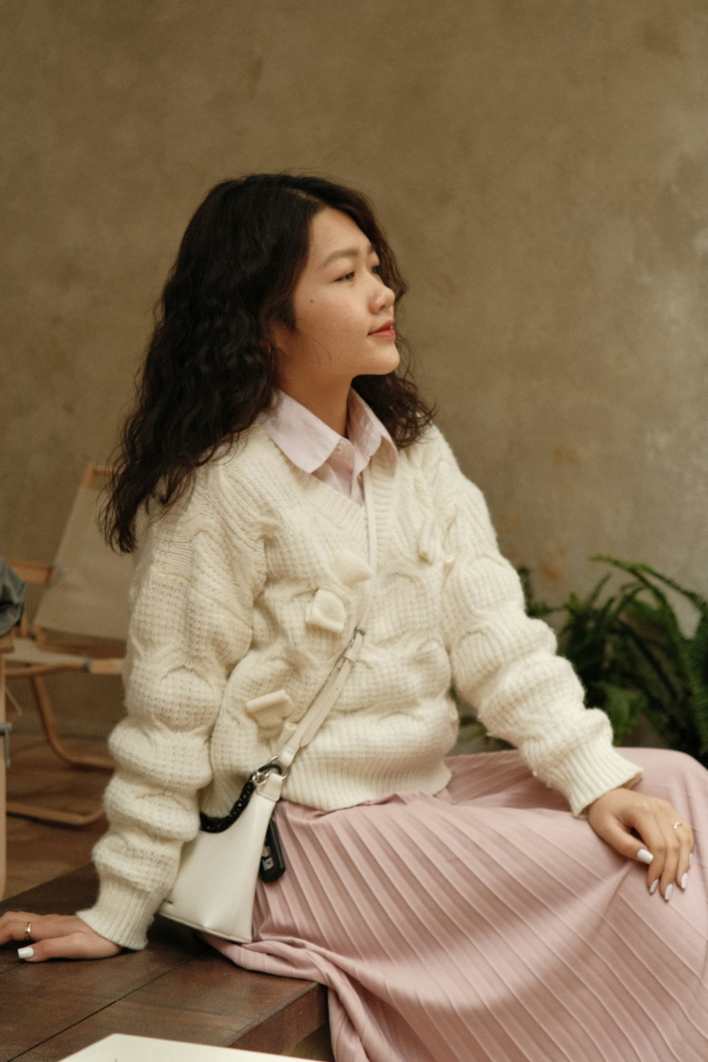 a woman sitting on a table in a pink skirt