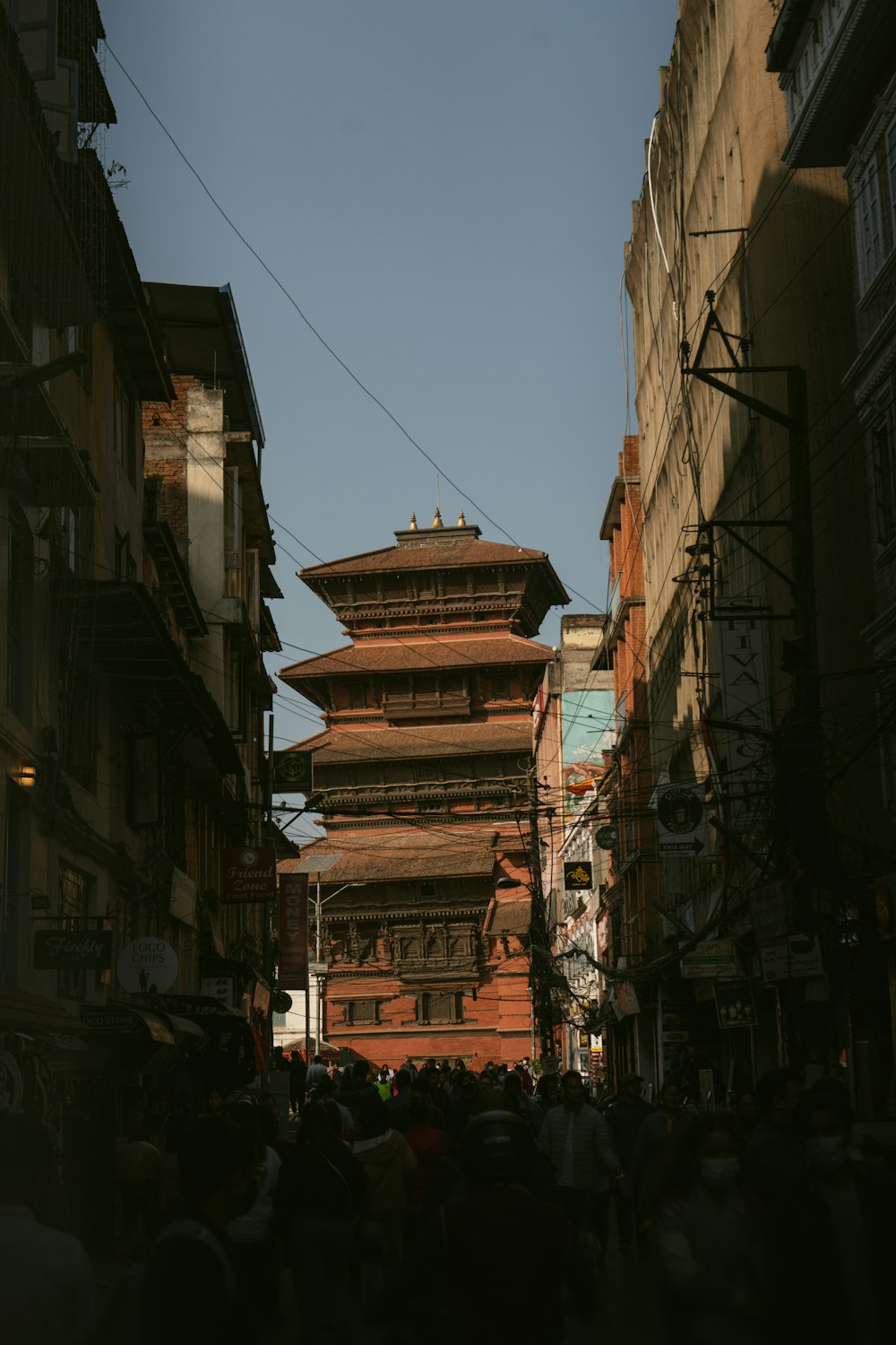 a group of people walking down a street next to tall buildings