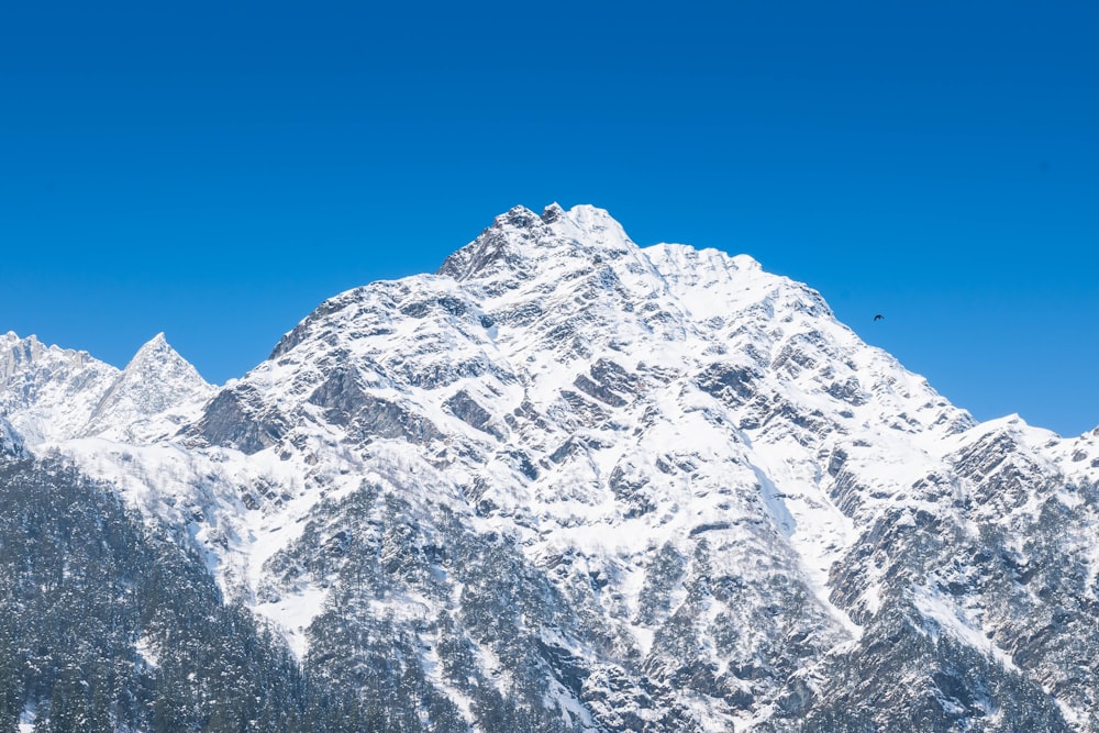 a large mountain covered in snow under a blue sky