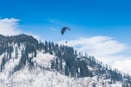 a paraglider is flying over a snowy mountain