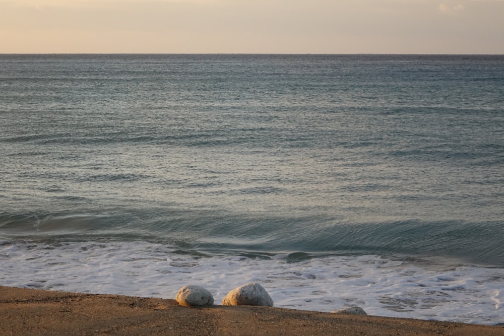 a couple of rocks sitting on top of a sandy beach