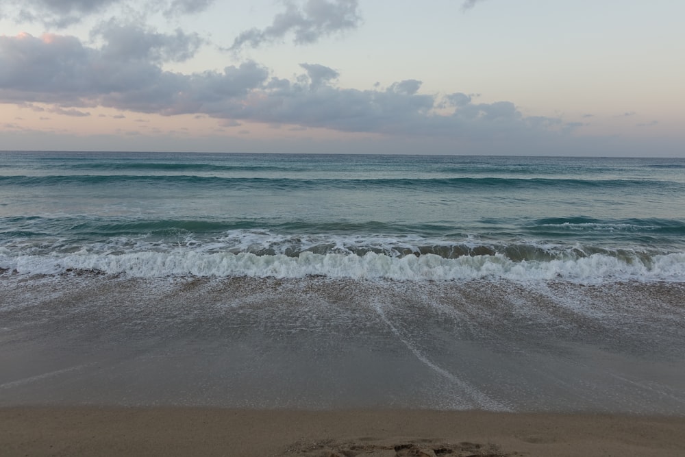 a sandy beach with waves coming in to shore