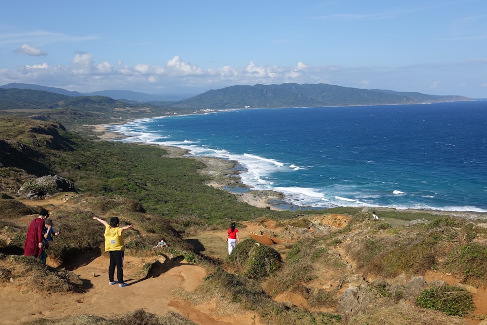 a group of people standing on top of a hill next to the ocean