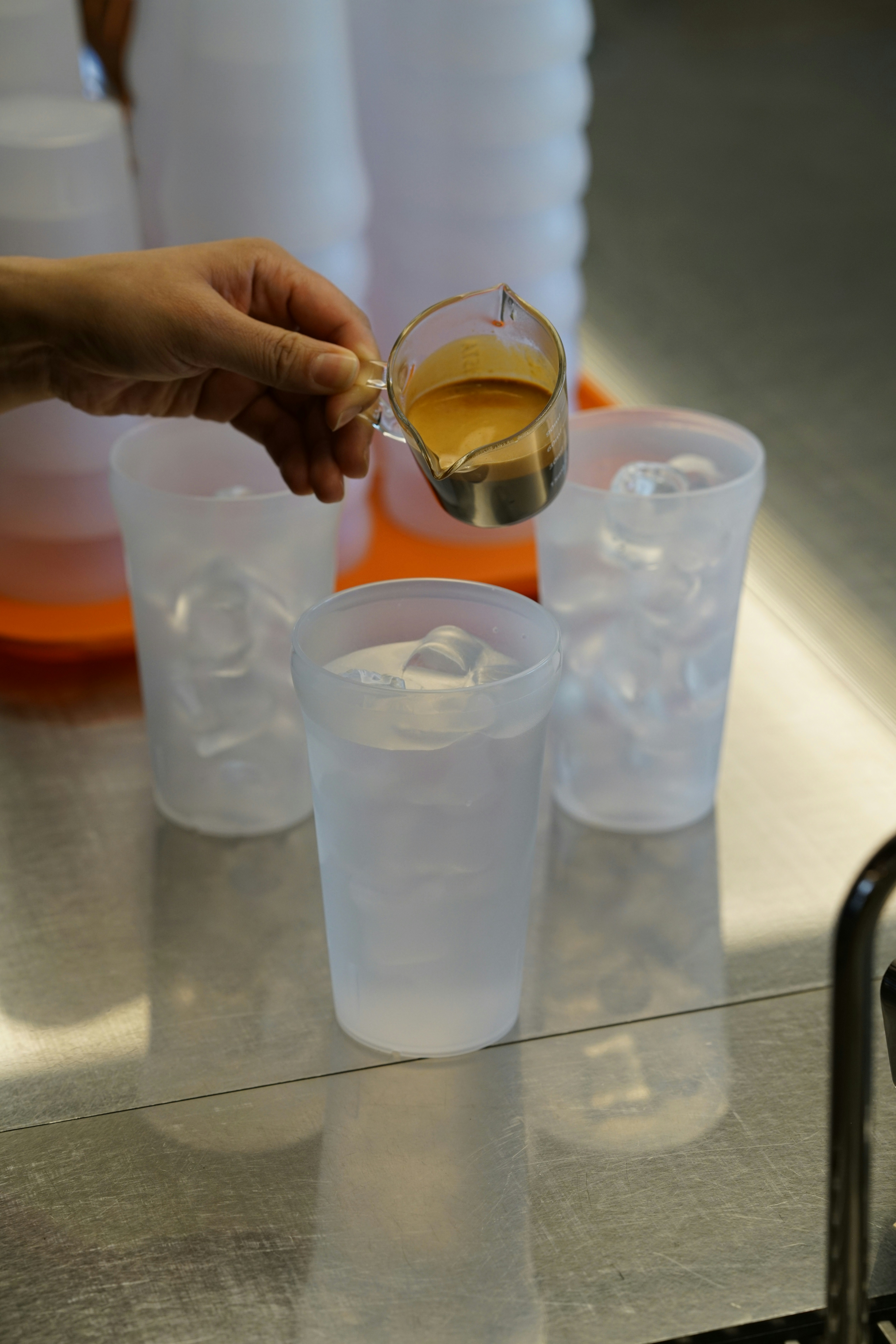 Eine Person gießt ein Getränk in Plastikbecher