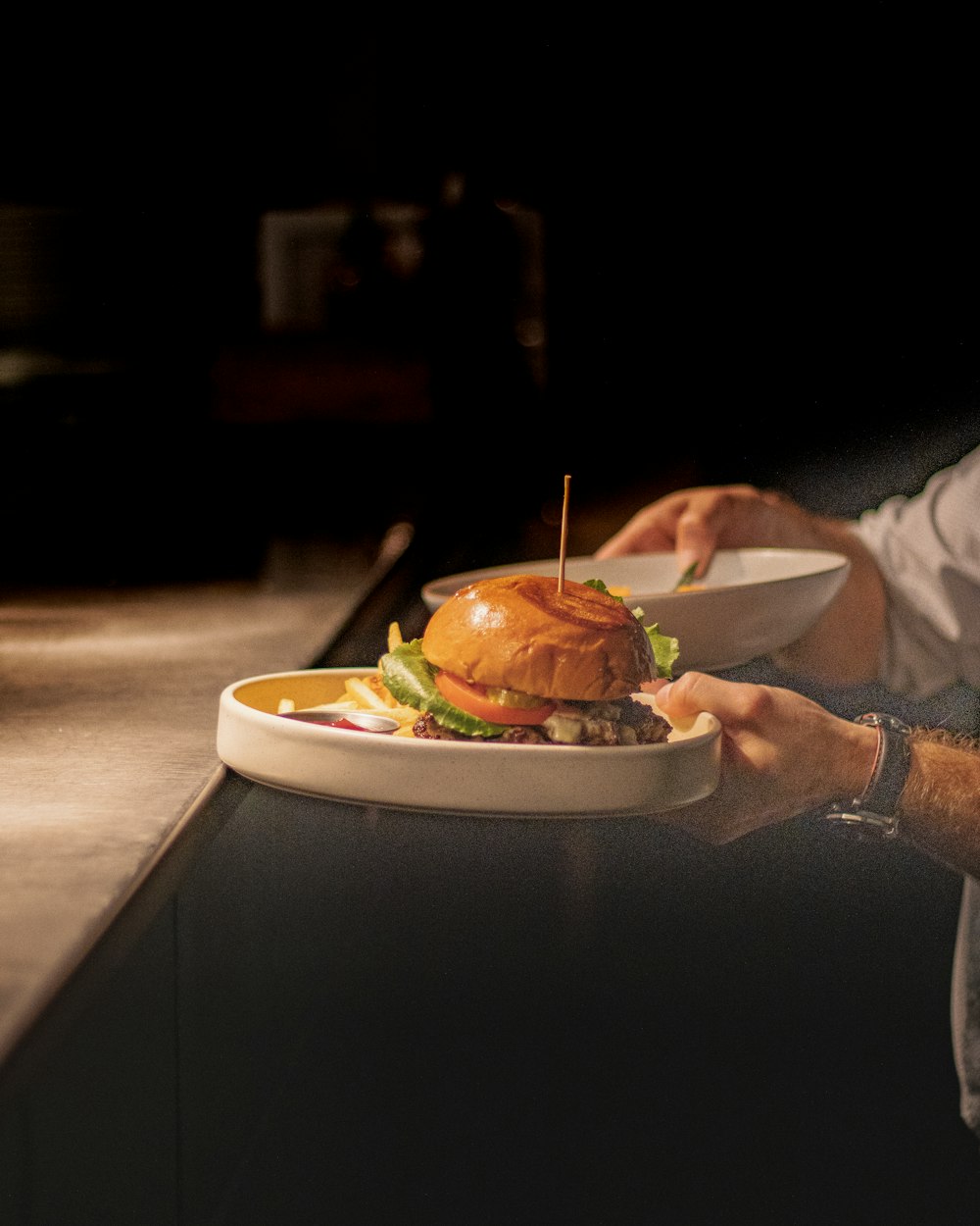 a man holding a plate with a hamburger on it