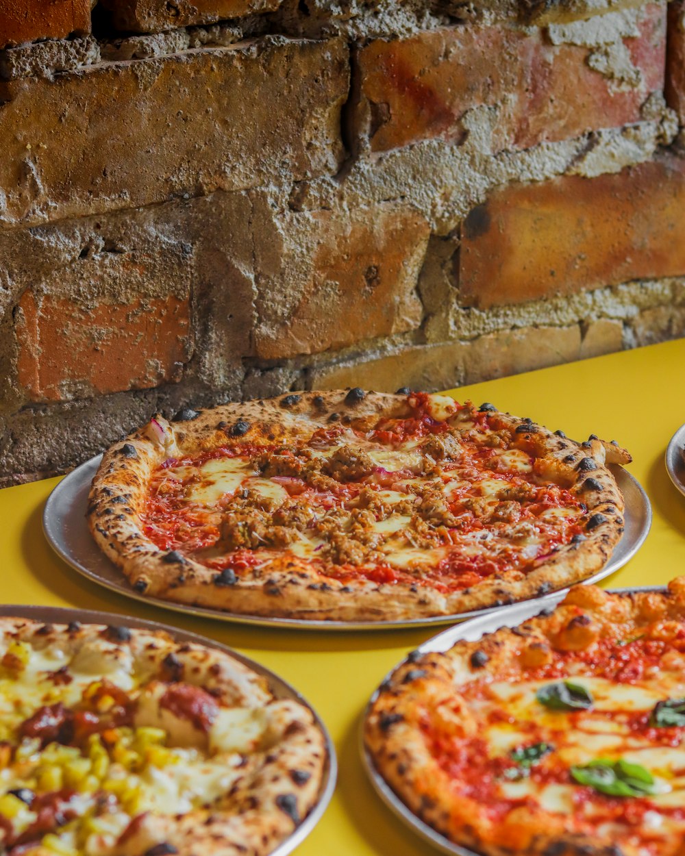 a table topped with three different types of pizza