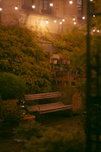 A cozy patio scene featuring a wooden outdoor bar table set surrounded by lush greenery.