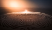 A vast array of solar panels is arranged in concentric circles around a central tower with a bright light, likely depicting a solar power plant. The setting appears to be a desert with a hazy sunrise or sunset casting an orange glow across the landscape.