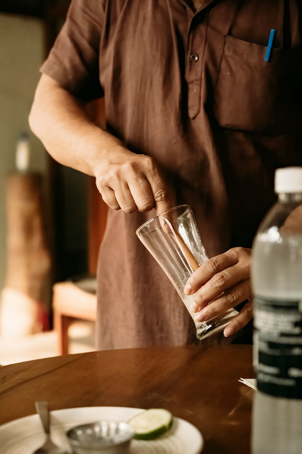 a man holding a glass on top of a wooden table