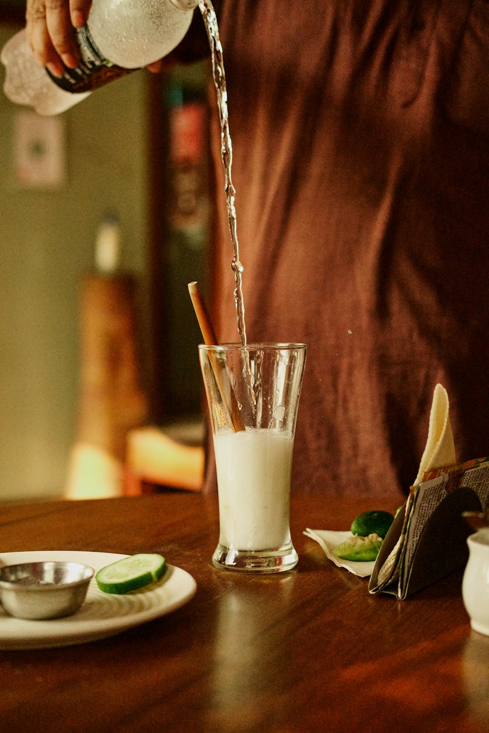 a person pouring a drink into a glass