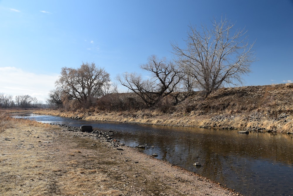 a river running through a dry grass covered field