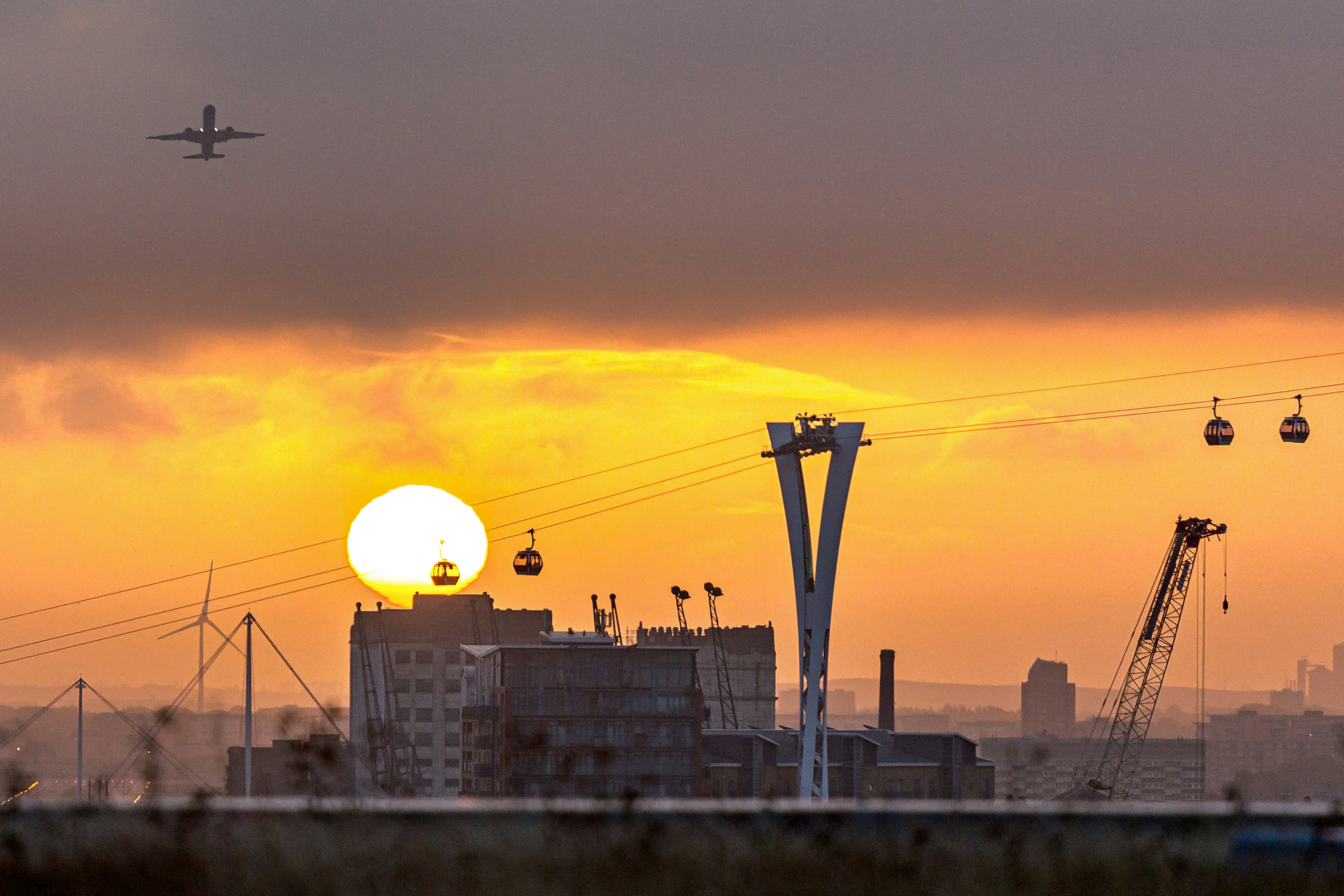 a plane flying over a city at sunset
