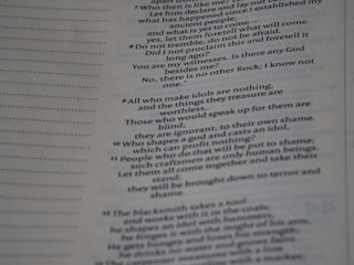 The image contains a close-up view of a page from a book with text focused on religious or philosophical content discussing gods and idols. The text appears on the right side of the page, with a margin on the left showing horizontal dotted lines.