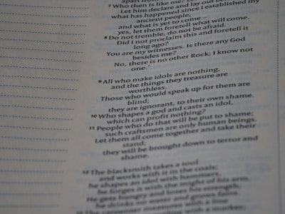 The image contains a close-up view of a page from a book with text focused on religious or philosophical content discussing gods and idols. The text appears on the right side of the page, with a margin on the left showing horizontal dotted lines.