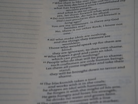 The image contains a close-up view of a page from a book with text focused on religious or philosophical content discussing gods and idols. The text appears on the right side of the page, with a margin on the left showing horizontal dotted lines.