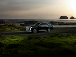 Wide shot of a stylish SUV in black and gold colors on a scenic coastal road.