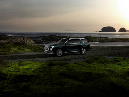 A sleek Nusantara Luxe SUV parked on a scenic Indonesian coastal road at sunset.