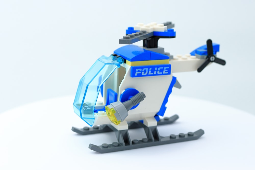 Un hélicoptère de police Lego est montré sur une surface blanche