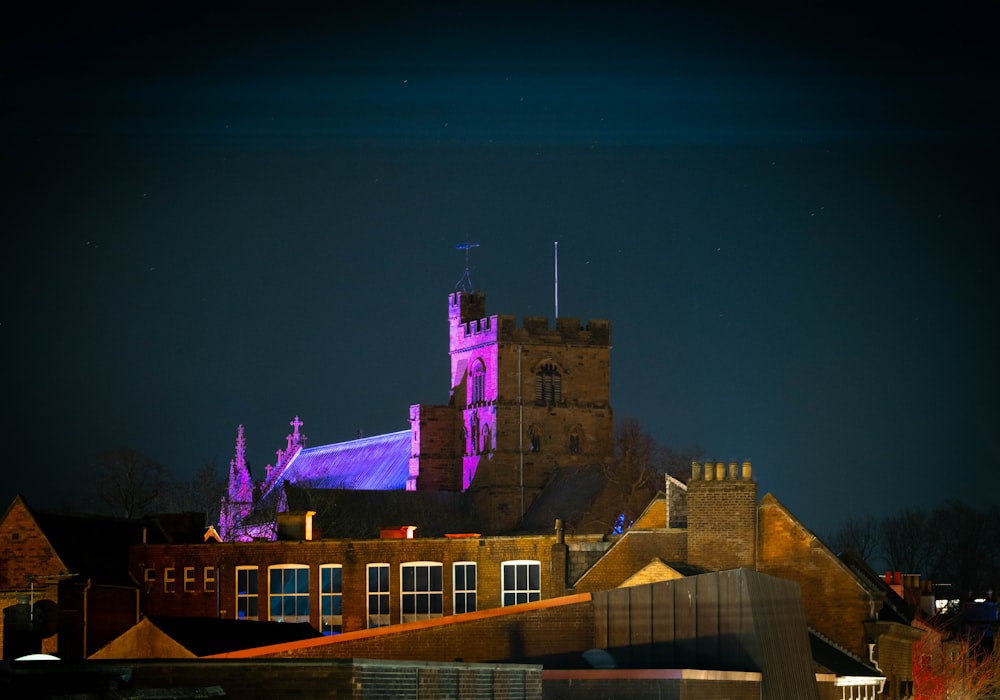 a castle lit up at night with the moon in the sky