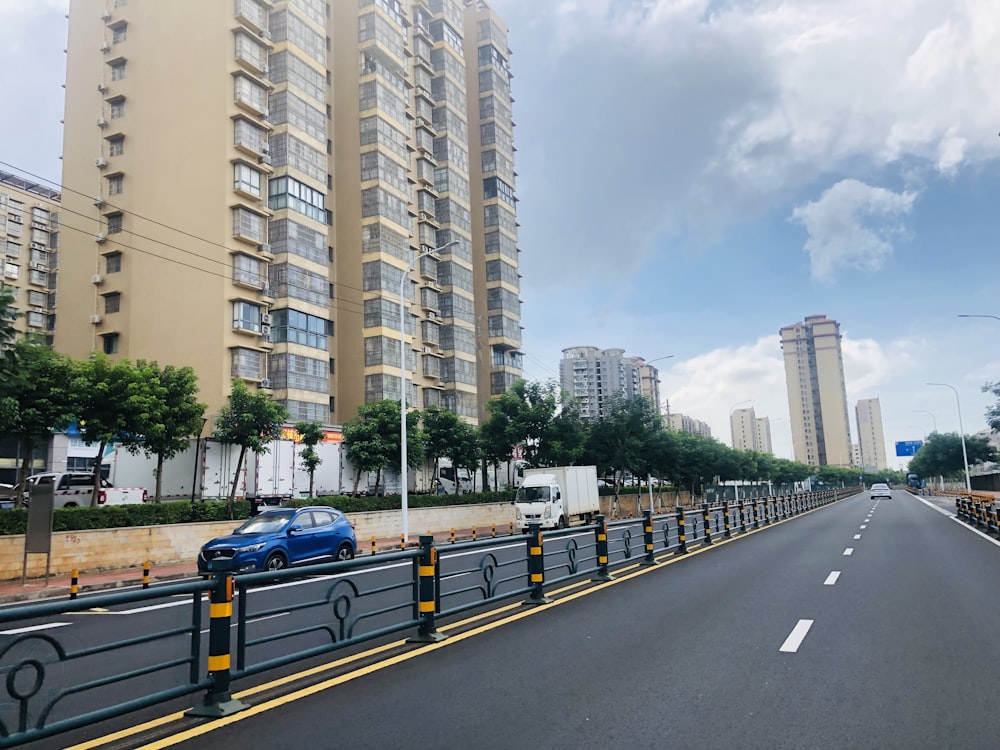 a blue car driving down a street next to tall buildings