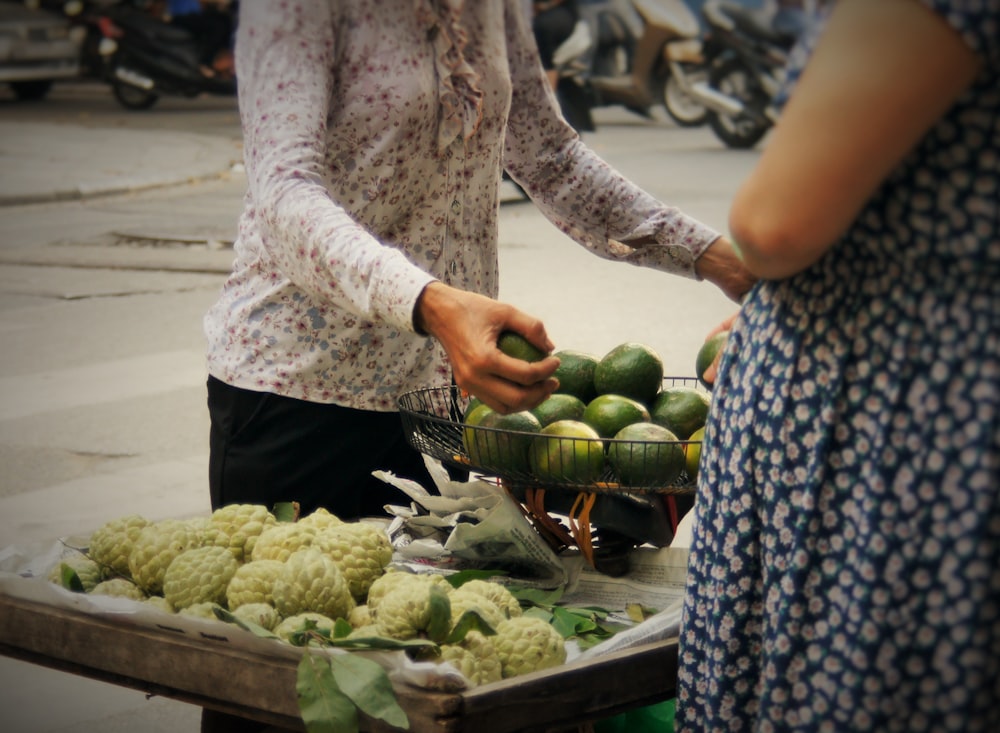 a woman standing next to a table filled with fruits and vegetables