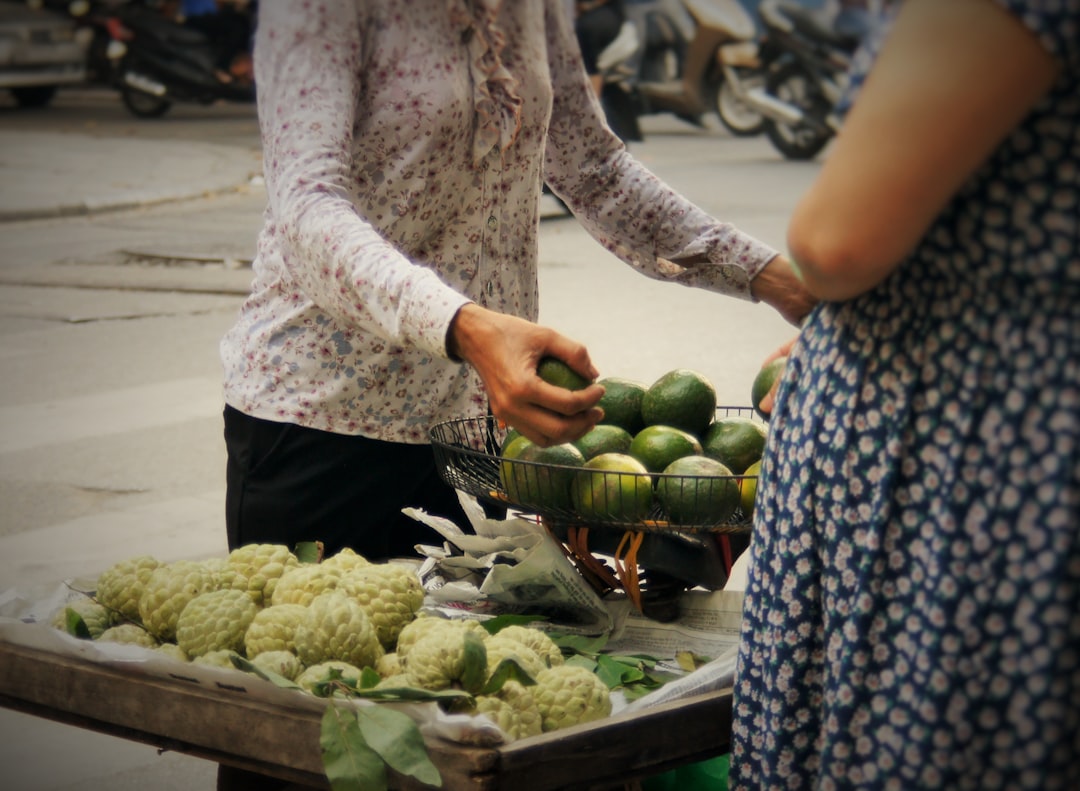 a woman standing next to a table filled with fruits and vegetables,