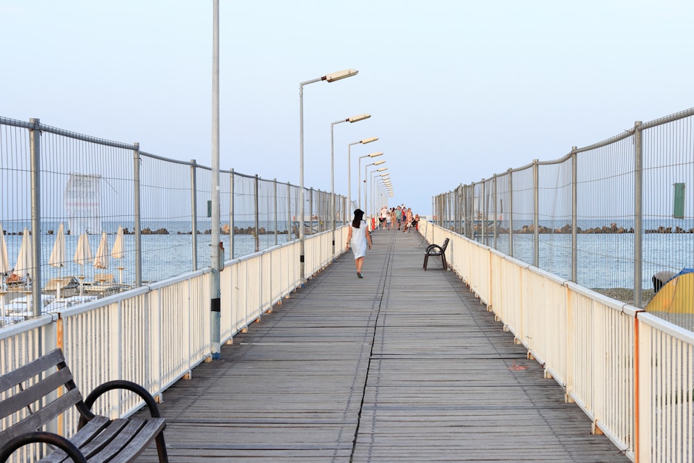 a woman walking across a bridge next to the ocean