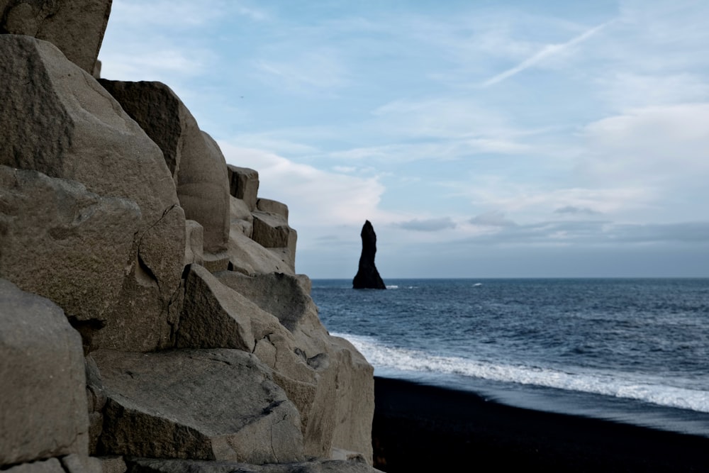 a black sand beach with a rock formation in the foreground