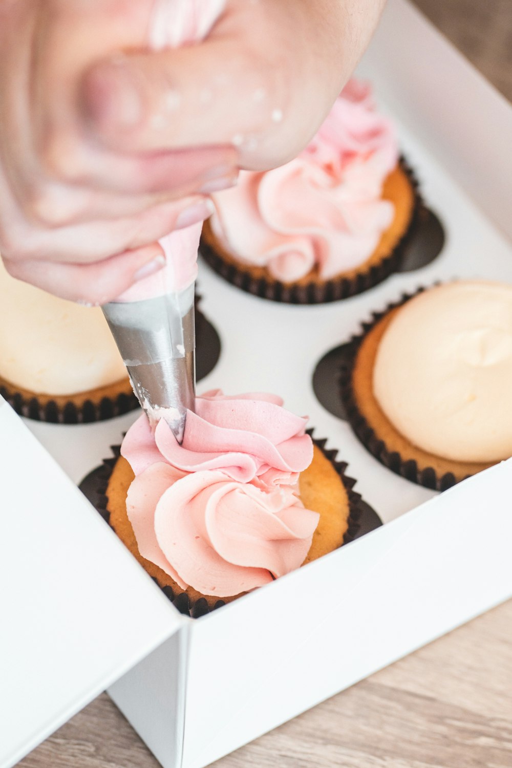 a person is decorating cupcakes in a box