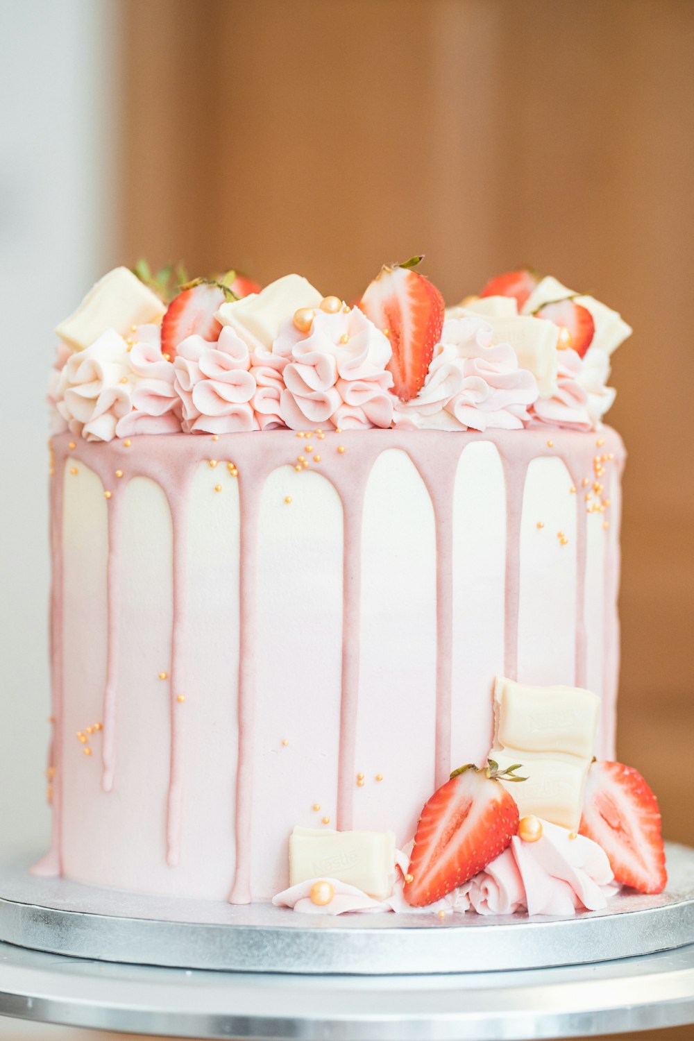 a pink cake with white frosting and strawberries on top
