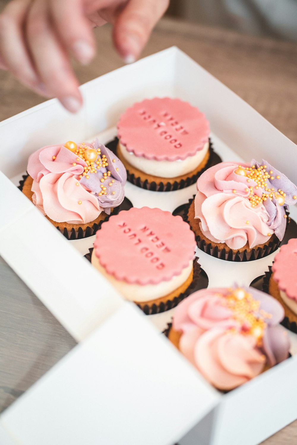 a box of cupcakes with pink frosting