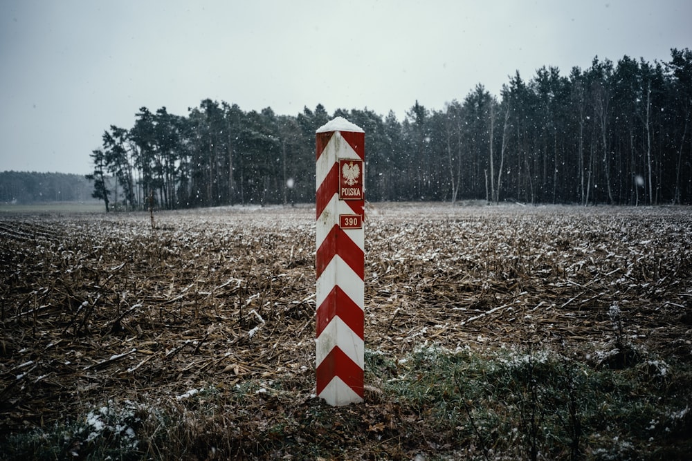 a red and white striped sign in a field