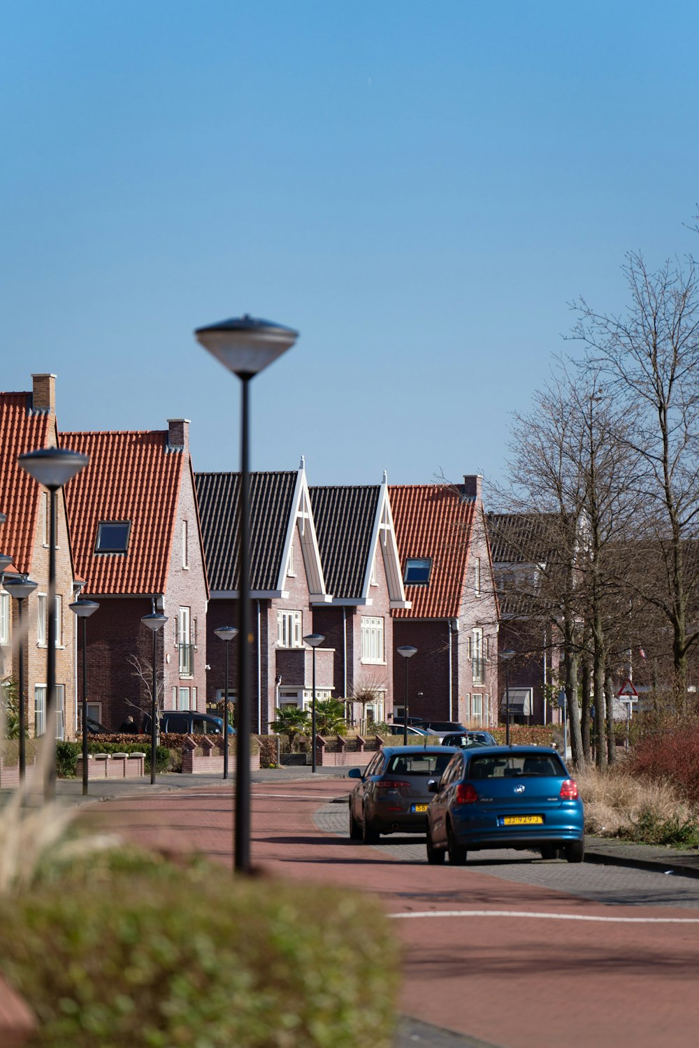 a blue car driving down a street next to a row of houses