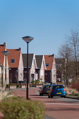 a blue car driving down a street next to a row of houses