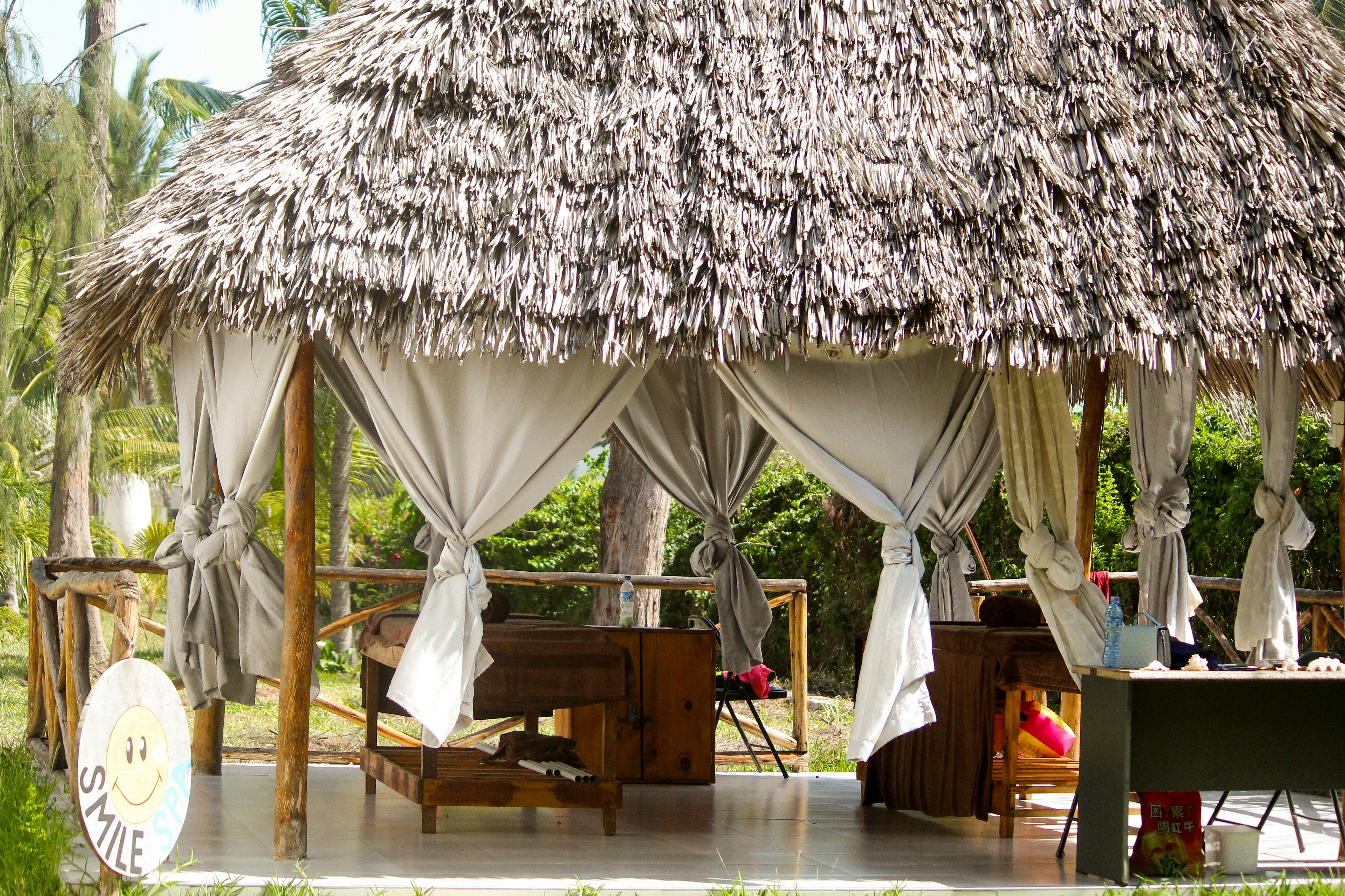 a gazebo with a thatched roof in a tropical setting