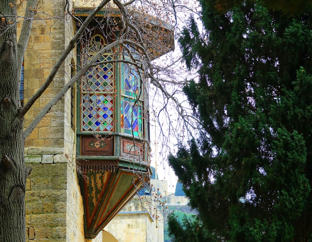 a building with a stained glass window and a tree in front of it