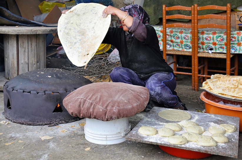 A warm Moroccan kitchen where an Amazigh family is preparing traditional bread over an open fire.
