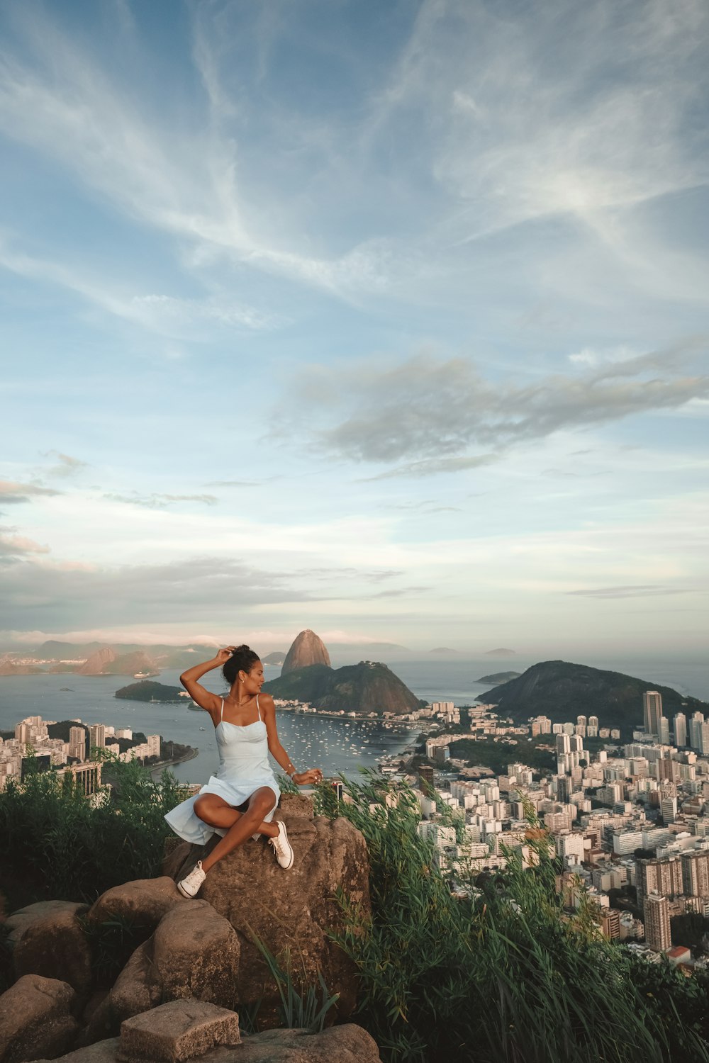 a woman sitting on top of a rock next to the ocean