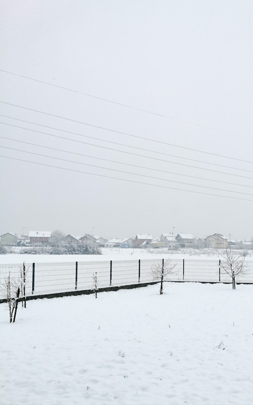 a field covered in snow next to a fence