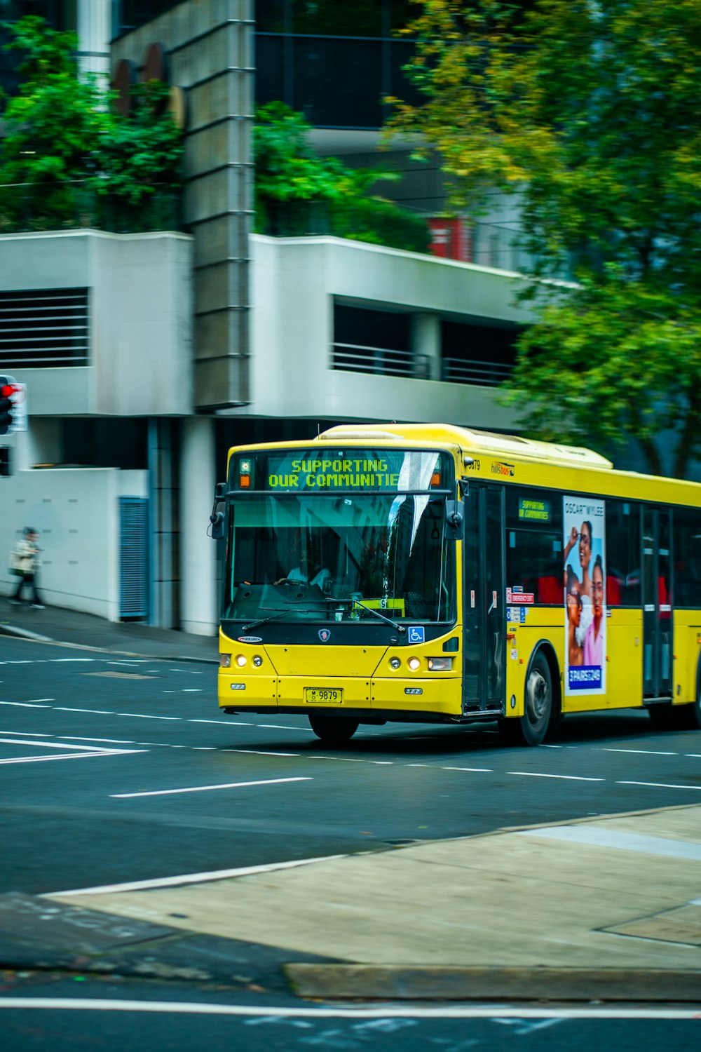 a yellow bus driving down a street next to a tall building