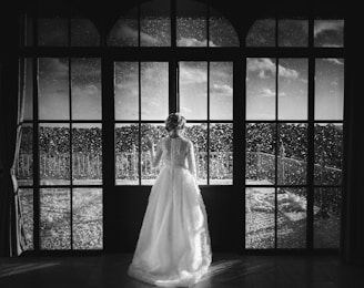 A serene moment of a bride looking out a window, her hair and makeup perfectly done.