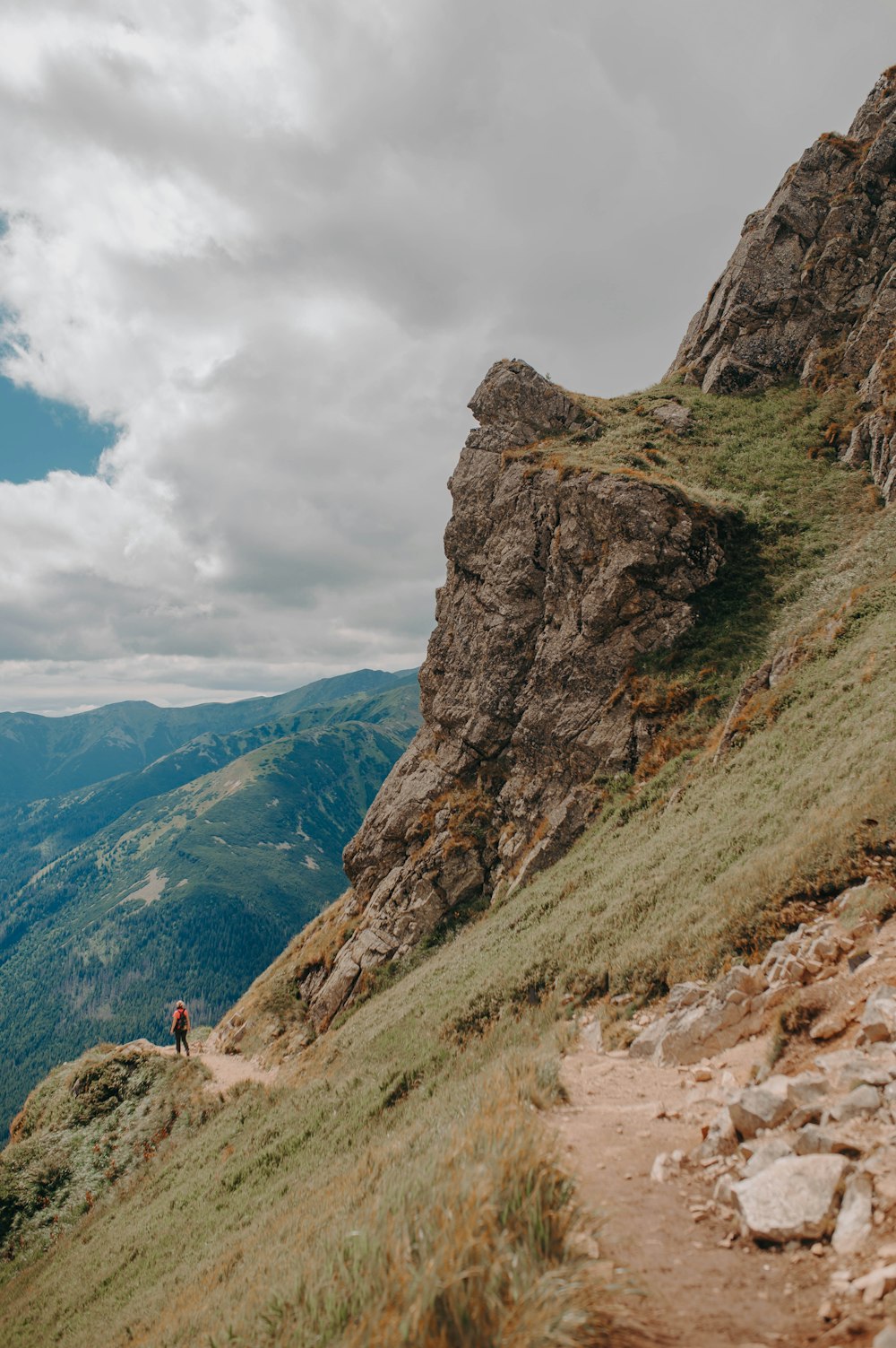 a person walking up a mountain trail on a cloudy day