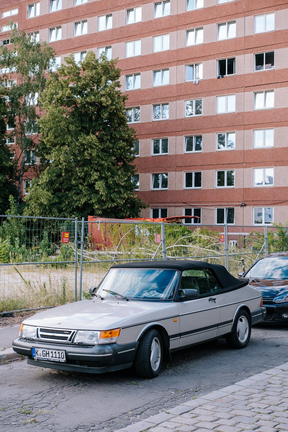 a silver car parked in front of a tall building