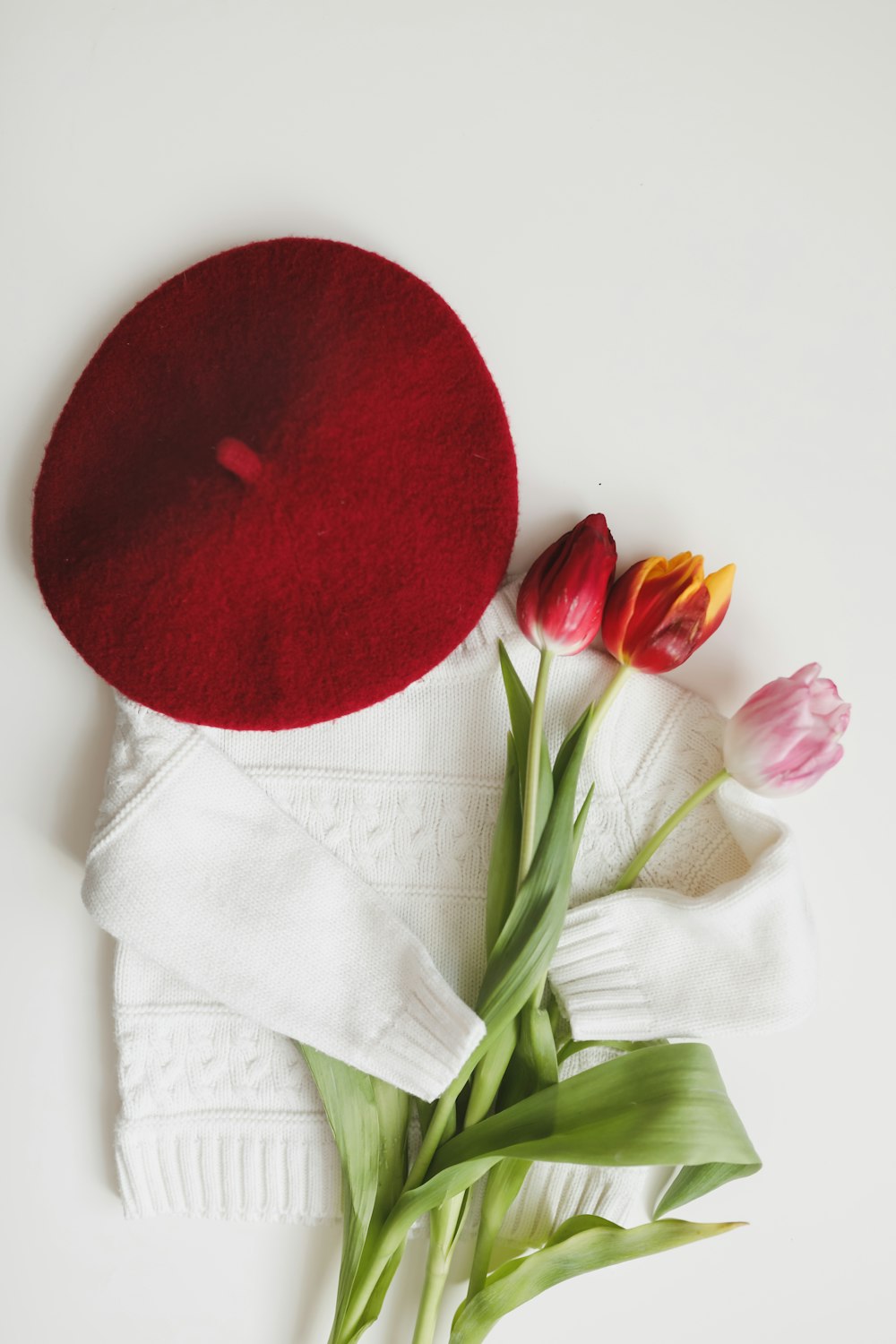 tulipanes y un suéter blanco sobre una superficie blanca