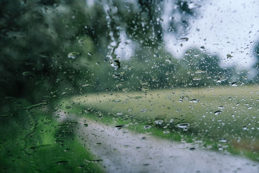 una vista di una strada attraverso una finestra coperta di pioggia