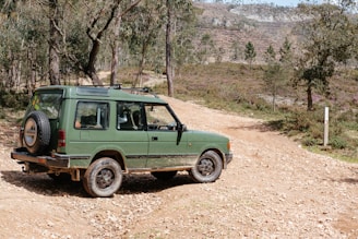 a green vehicle parked on a dirt road