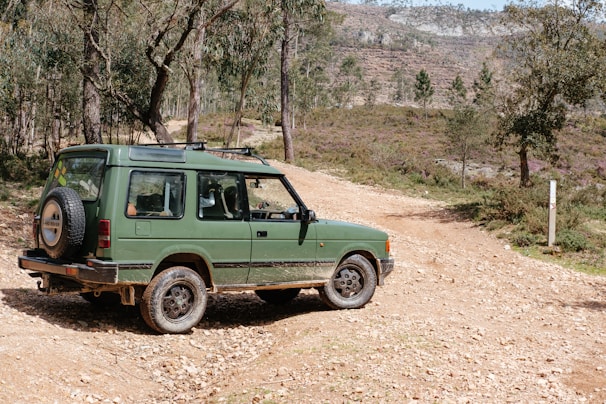 a green vehicle parked on a dirt road