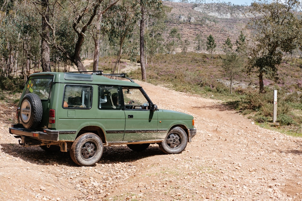 Un vehículo verde estacionado en un camino de tierra