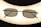 A pair of rectangular framed eyeglasses with dark lenses is centered against a bright, oval-shaped light source, creating a silhouette effect. The frame is thin and metallic, giving a sleek appearance.