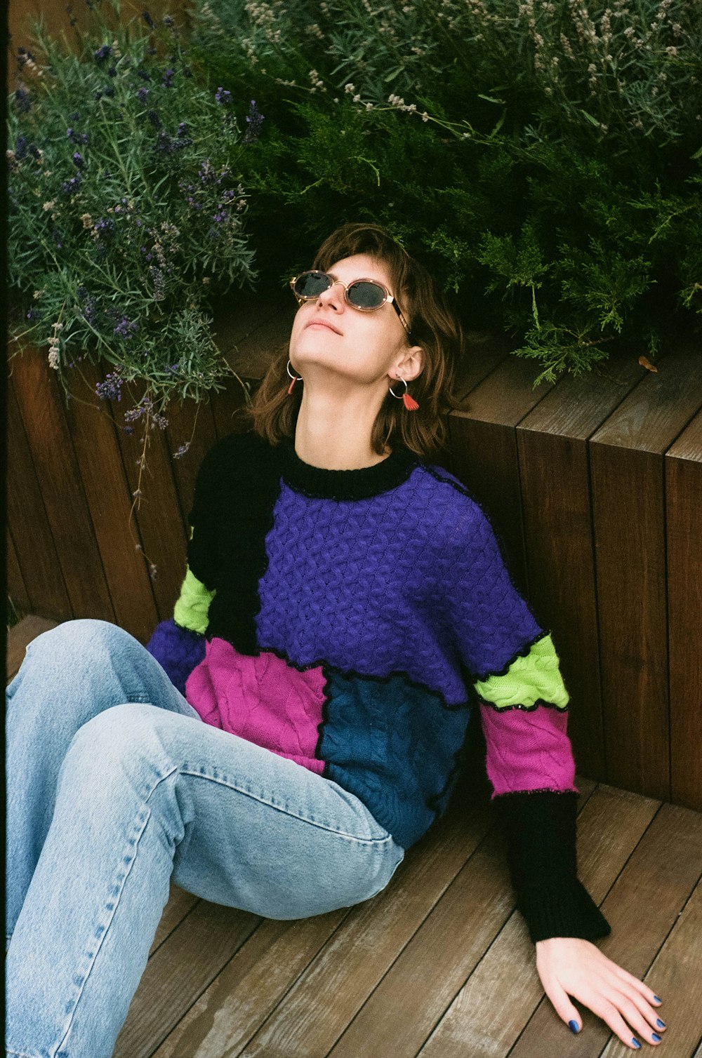 a woman sitting on a wooden floor next to a plant